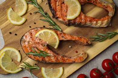 Photo of Tasty grilled salmon steaks and different ingredients on light grey table, flat lay