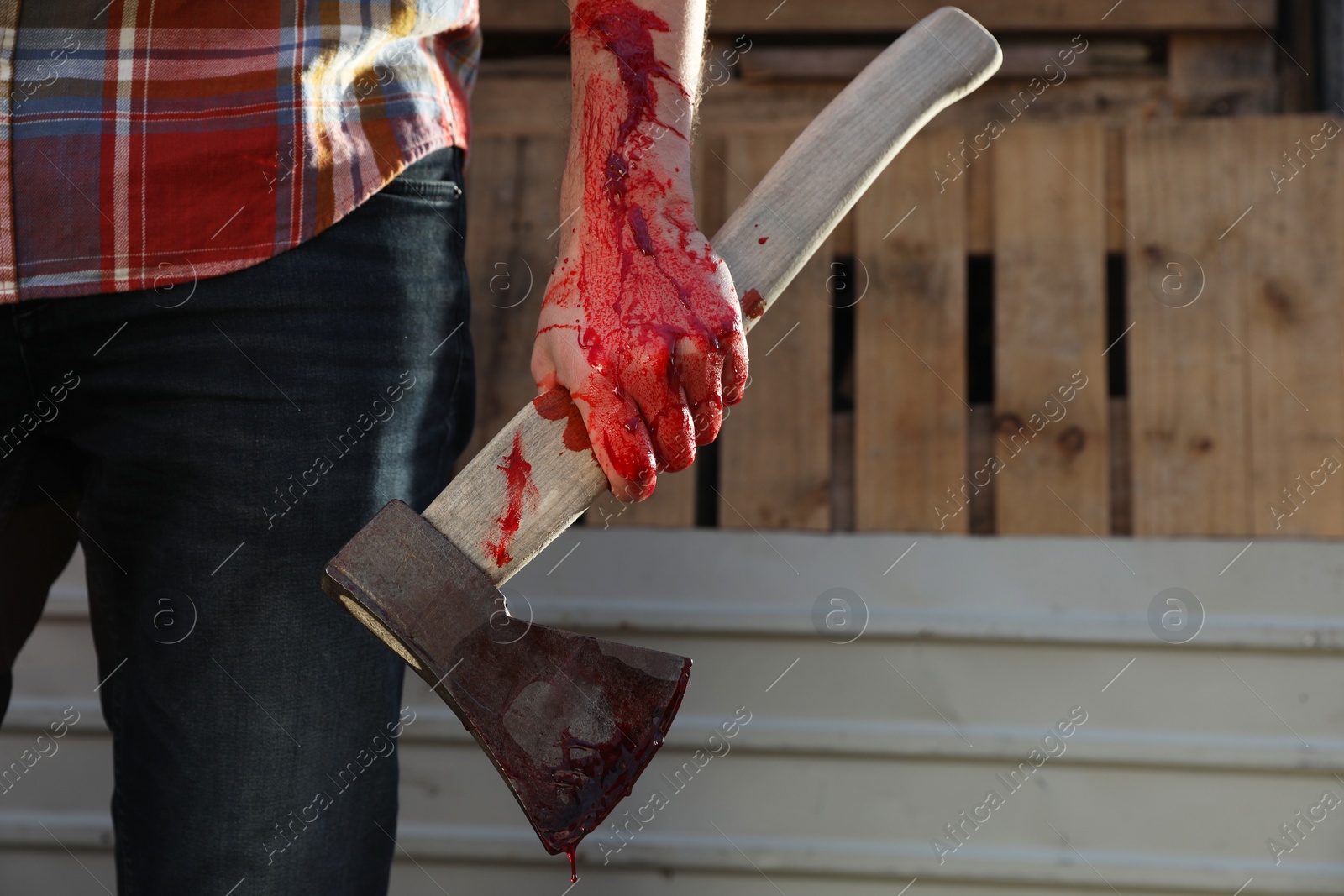 Photo of Man holding bloody axe outdoors, closeup. Space for text