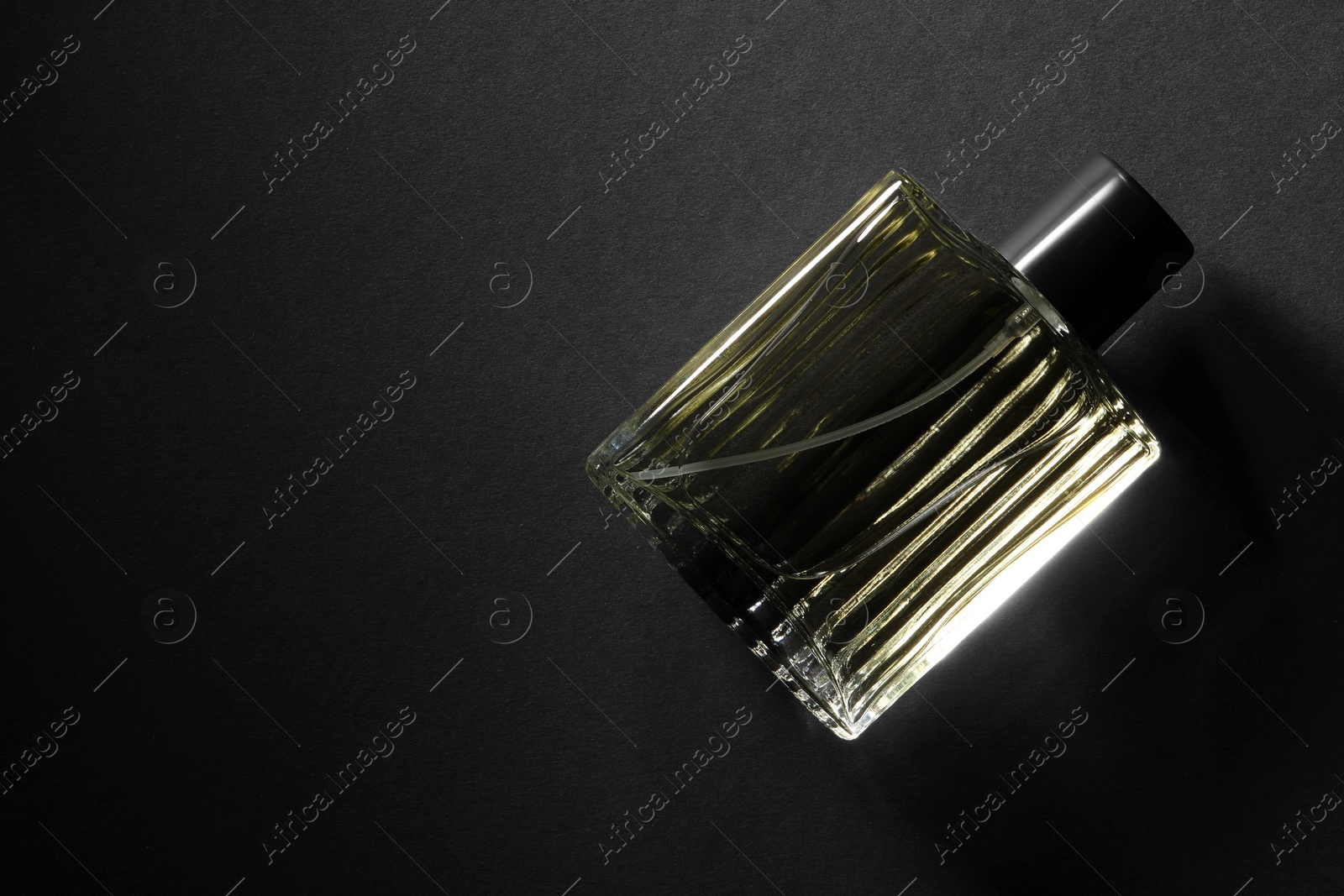 Photo of Luxury men`s perfume in bottle on black background, top view. Space for text