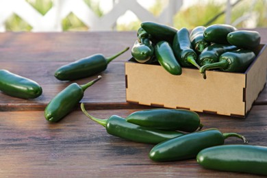 Photo of Fresh green jalapeno peppers on wooden table outdoors