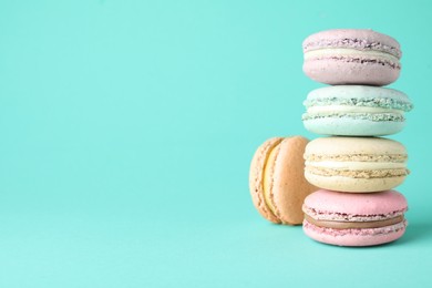 Photo of Delicious colorful macarons on turquoise background. Space for text