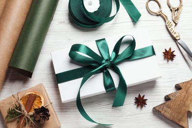 Photo of Flat lay composition with beautiful Christmas gift boxes and wrapping paper on white wooden table