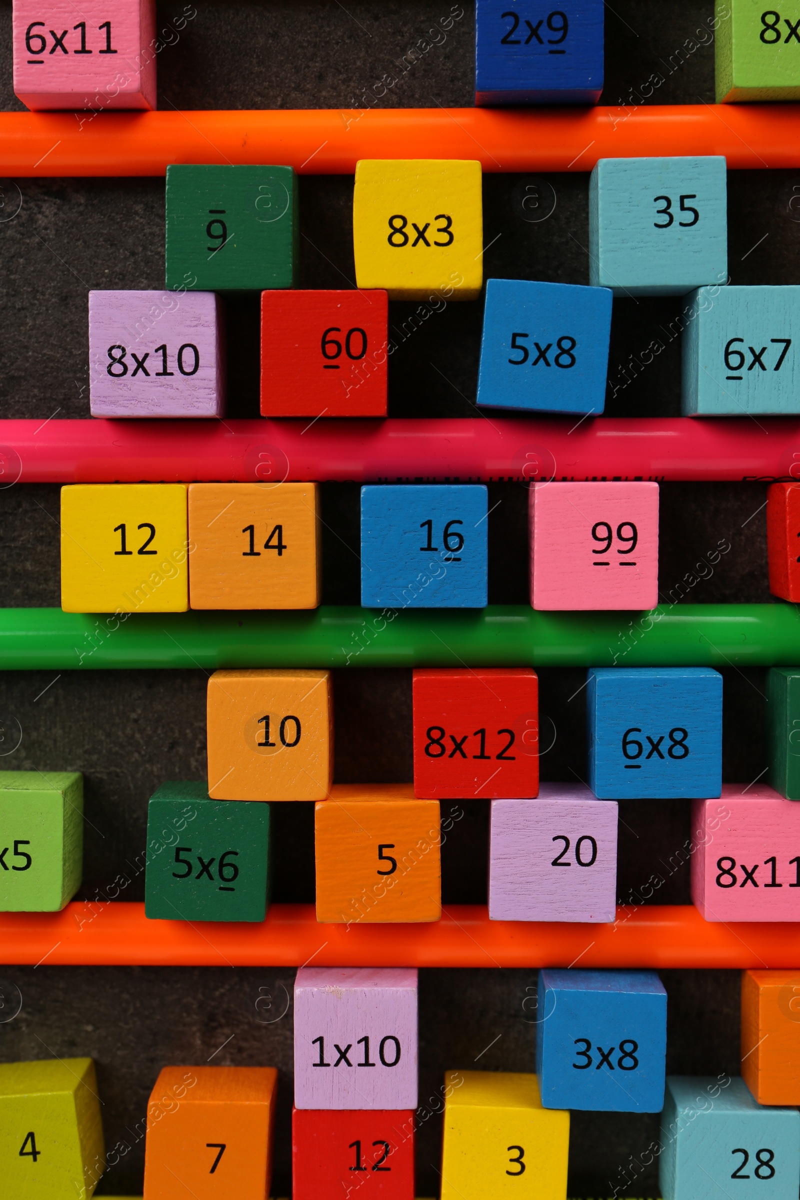 Photo of Many colorful cubes with numbers, multiplications and pencils on dark grey table, flat lay