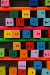Many colorful cubes with numbers, multiplications and pencils on dark grey table, flat lay