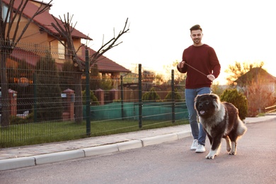 Young man walking his Caucasian Shepherd dog outdoors