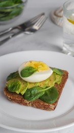 Tasty sandwich with boiled egg, avocado and spinach on white marble table, closeup