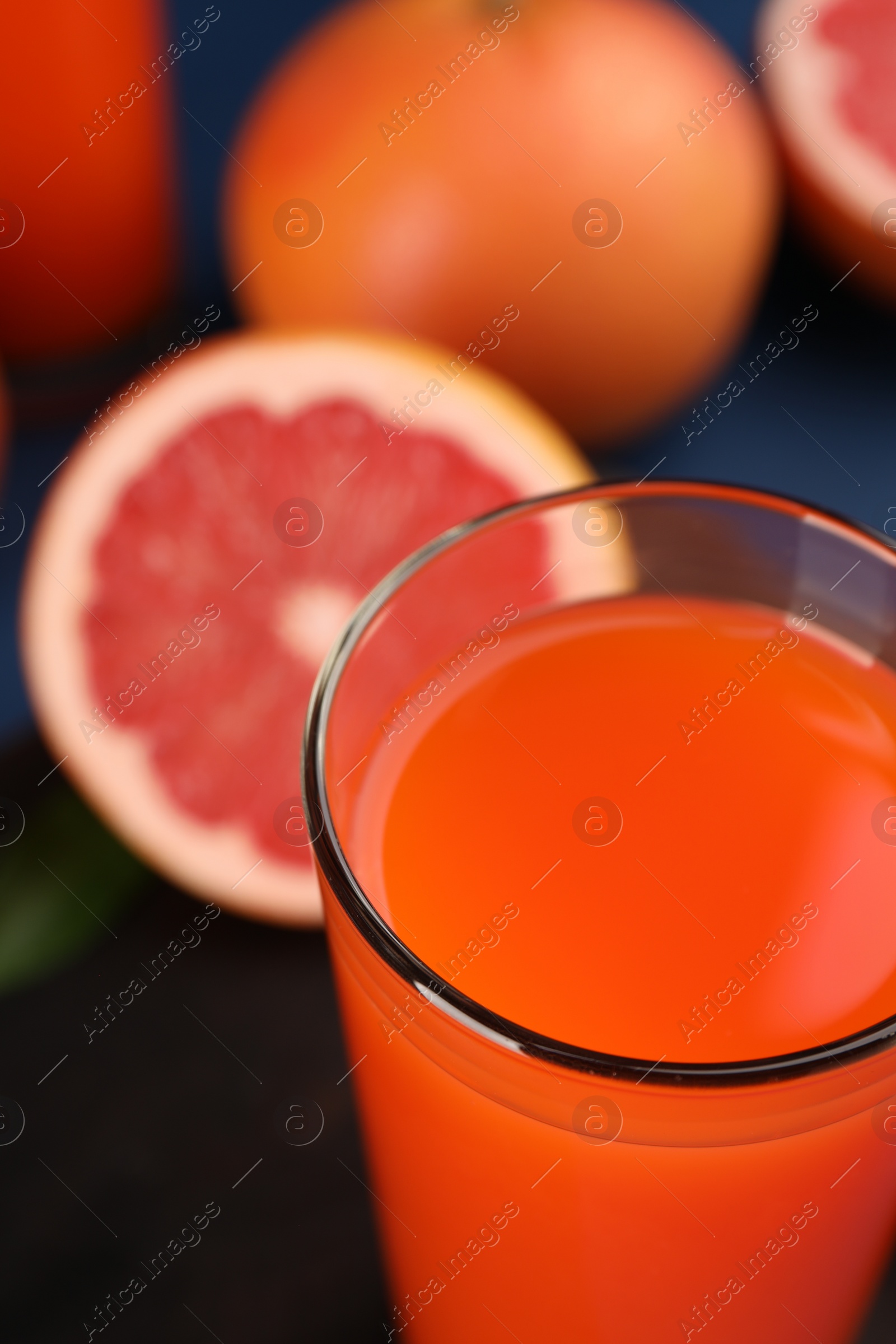 Photo of Tasty grapefruit juice in glass and fresh fruits on table, closeup