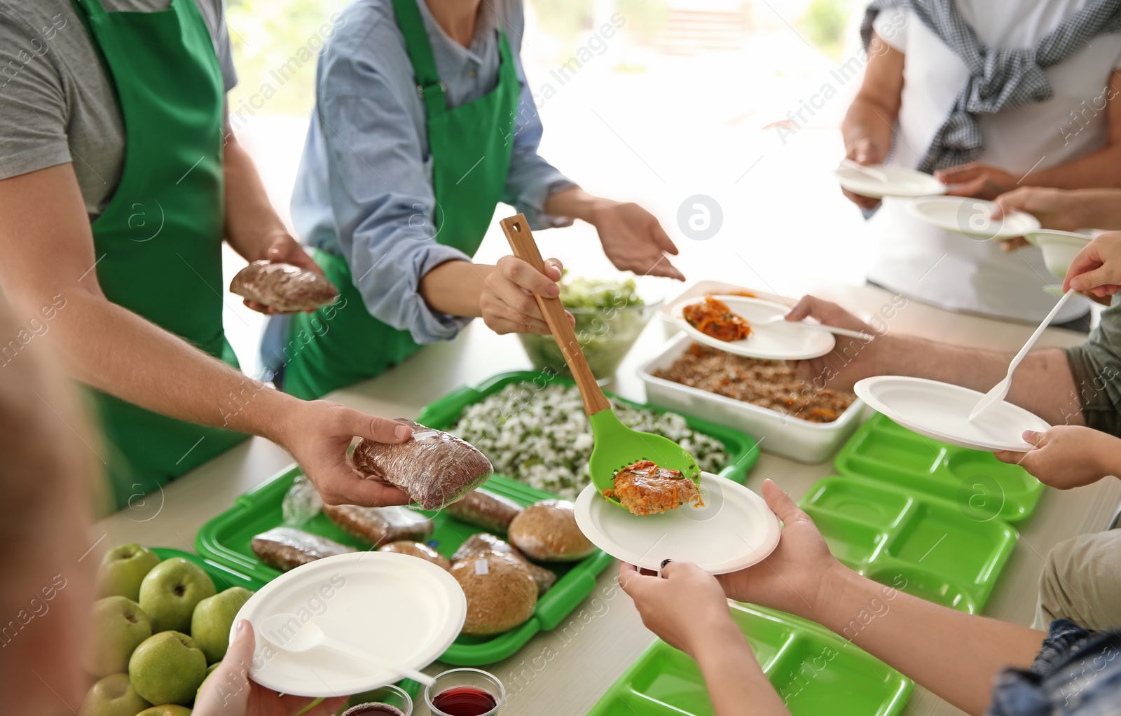 Photo of Volunteers serving food for poor people indoors