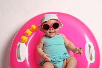 Cute little baby in sunglasses with inflatable ring on white background, top view