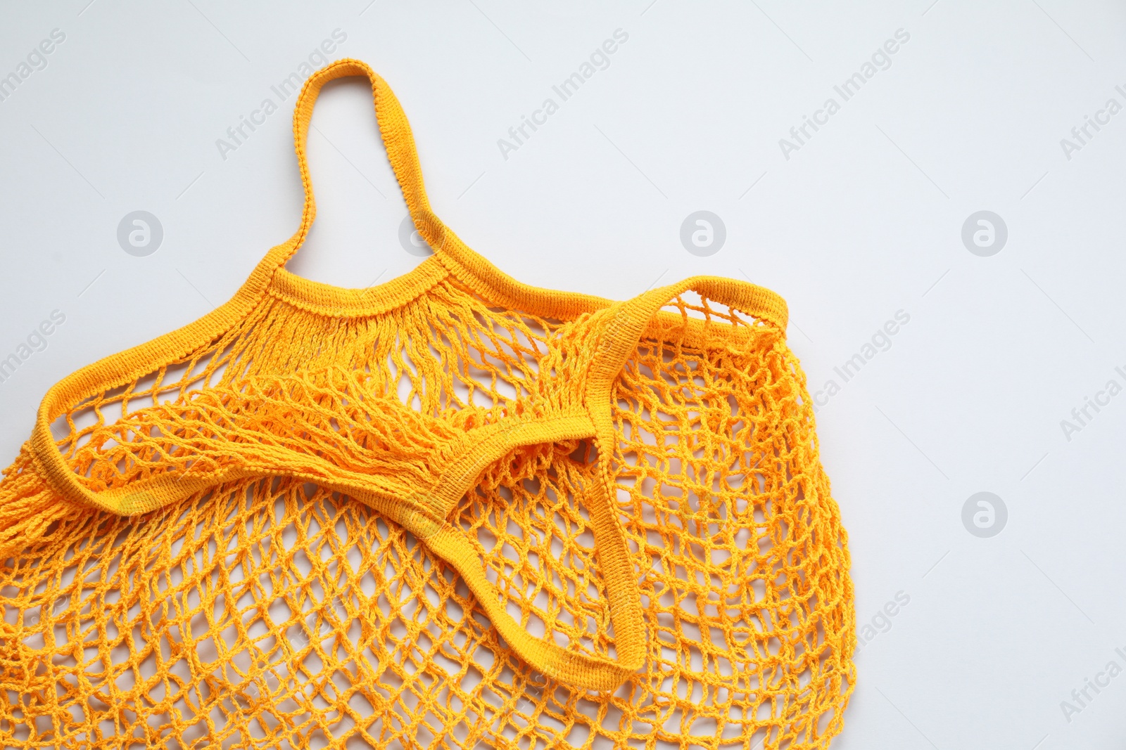 Photo of Orange string bag on light grey background, top view
