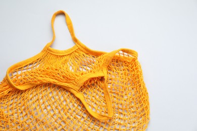 Orange string bag on light grey background, top view