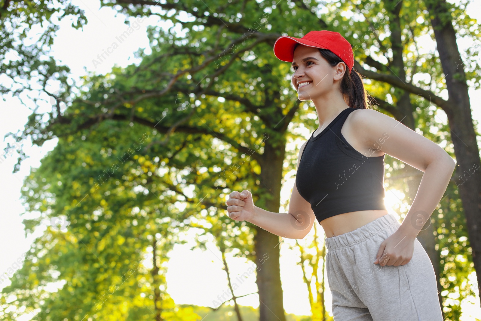 Photo of Young woman running outdoors in morning, low angle view. Space for text