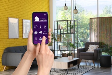 Woman using smart home control system via application on mobile phone indoors, closeup