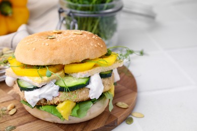 Photo of Tasty vegan burger with vegetables, sauce and patty on white table, closeup