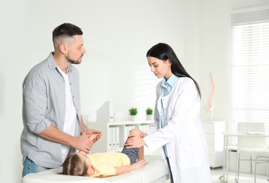 Professional orthopedist examining little patient's leg in clinic