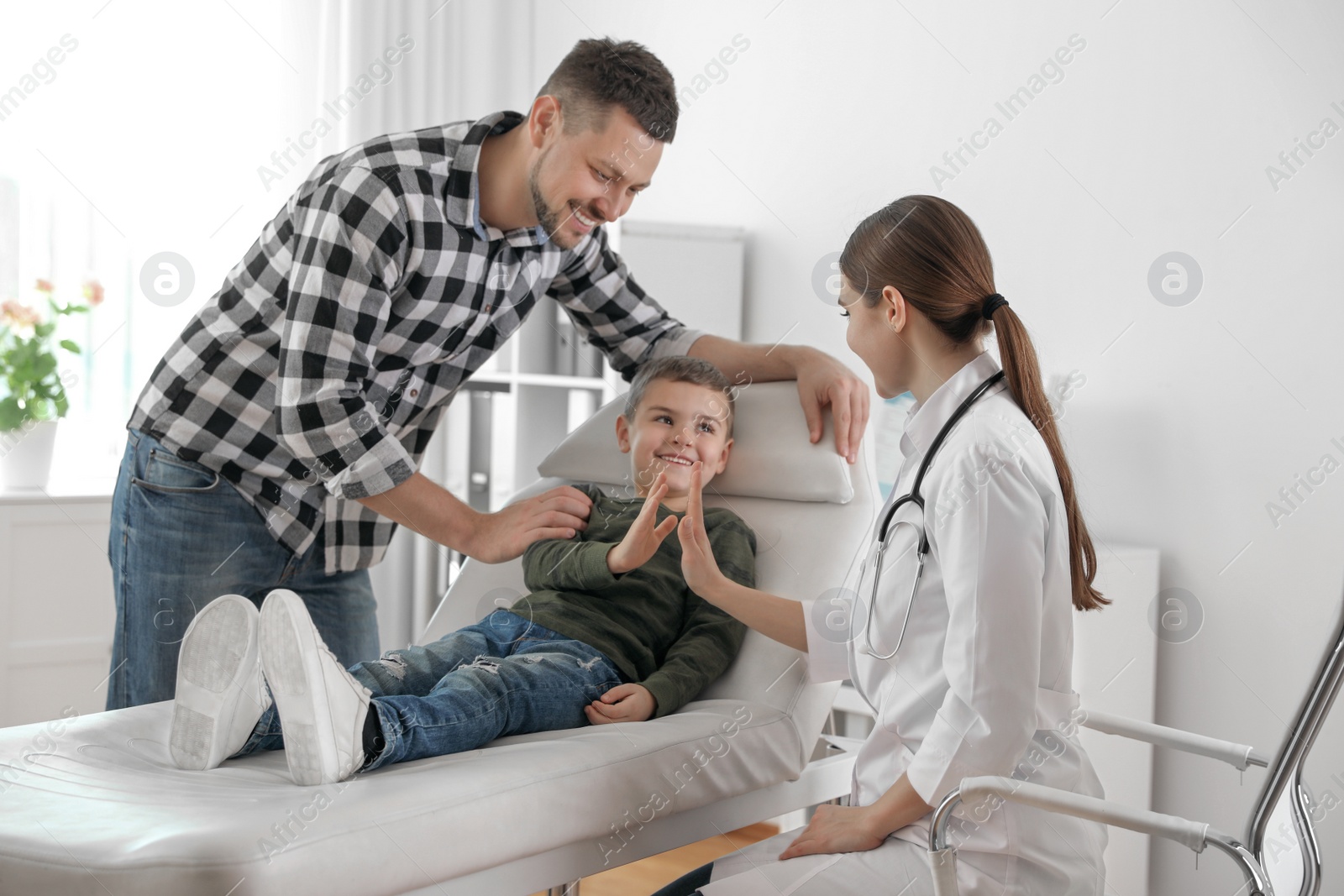 Photo of Father and son visiting pediatrician. Doctor working with patient in hospital