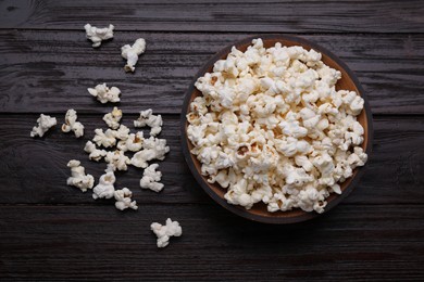 Photo of Tasty popcorn on black wooden table, flat lay