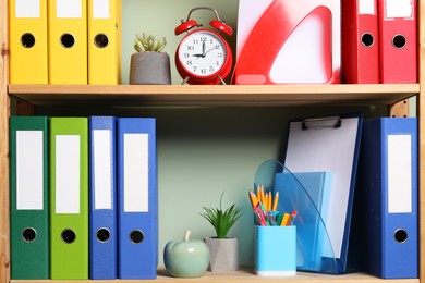 Photo of Colorful binder office folders and stationery on shelving unit indoors