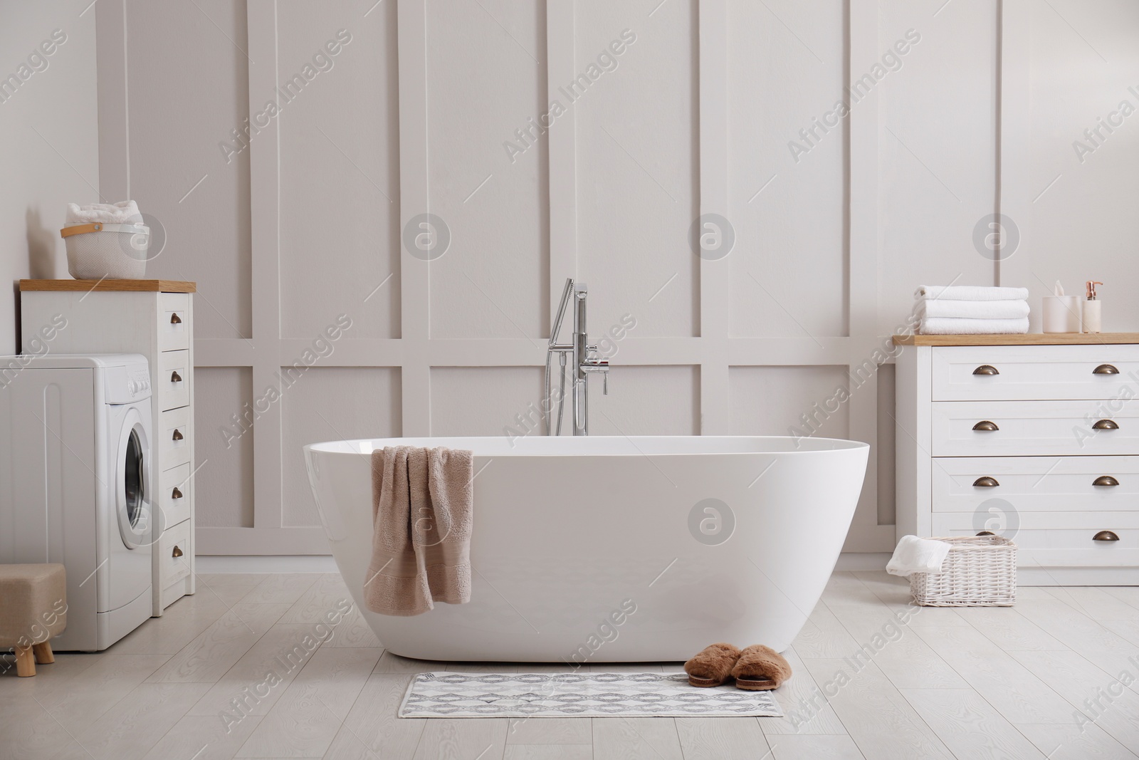 Photo of Stylish mat and slippers on floor near tub in bathroom. Interior design