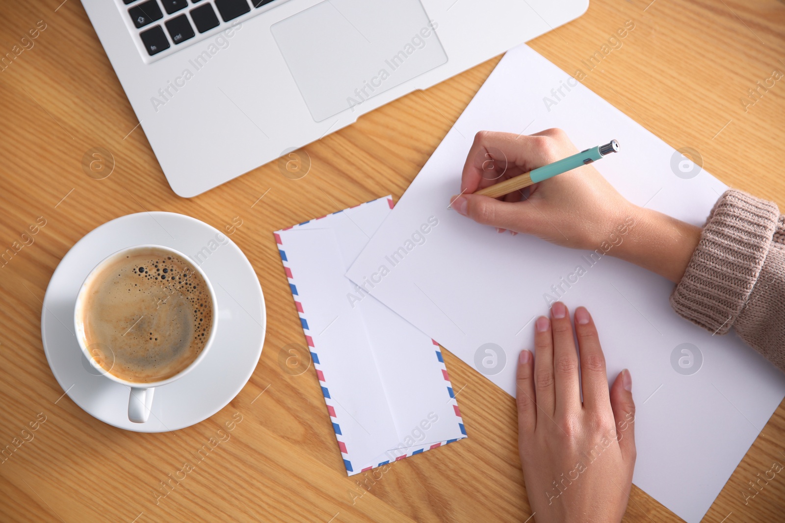 Photo of Woman writing letter at wooden table, top view