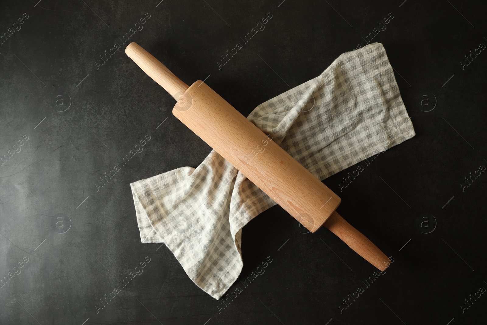 Photo of Rolling pin and kitchen towel on black table, top view