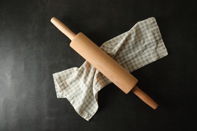 Photo of Rolling pin and kitchen towel on black table, top view