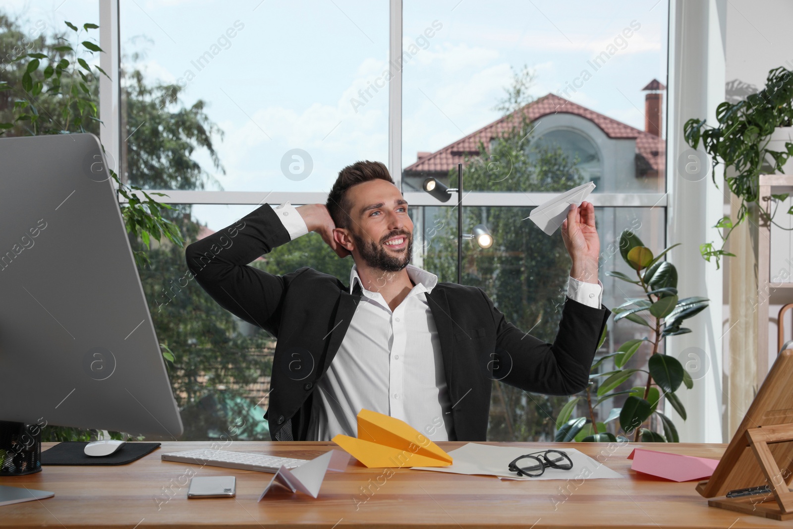 Photo of Handsome businessman playing with paper plane at desk in office