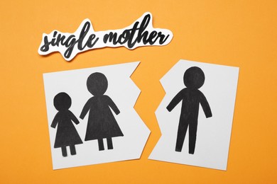 Photo of Being single mother after divorce concept. Paper cutouts demonstrating broken family on orange background, flat lay