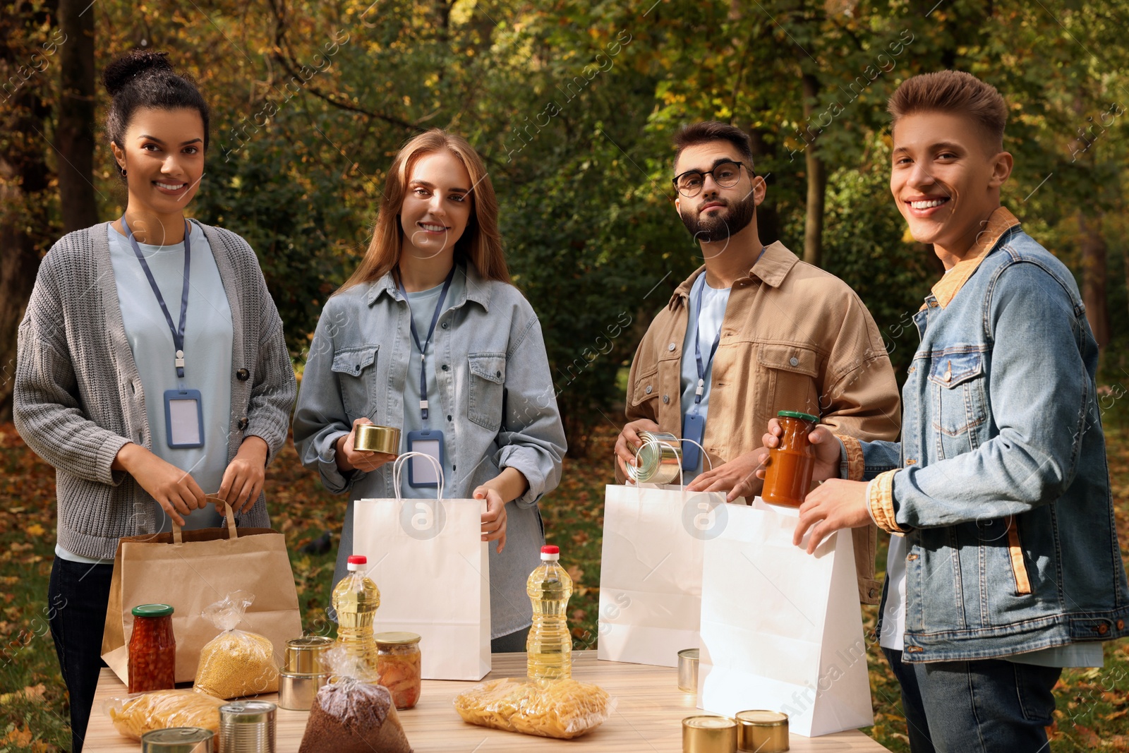 Photo of Portrait of volunteers packing food products at table in park