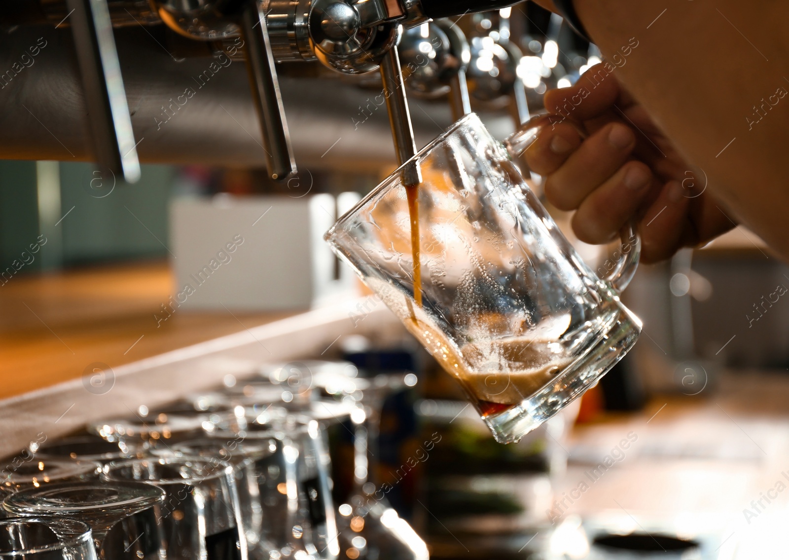 Photo of Bartender pouring beer into glass in pub, closeup