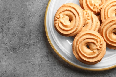 Photo of Plate with Danish butter cookies on grey background, top view. Space for text