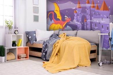 Image of Kid's room interior with comfortable bed. Fairytale themed wallpapers with castle and dragon
