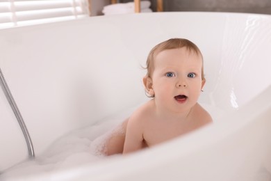 Photo of Cute little baby bathing in tub at home