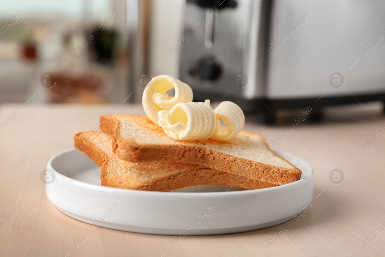 Photo of Plate with toasts and tasty butter curls on table