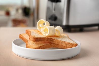 Plate with toasts and tasty butter curls on table