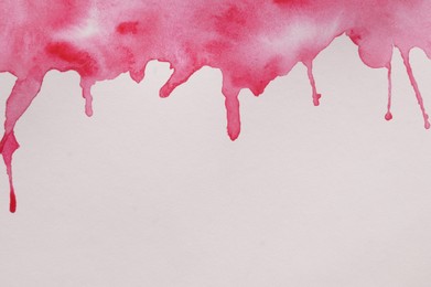 Photo of Magenta watercolor blots on white canvas, top view. Space for text