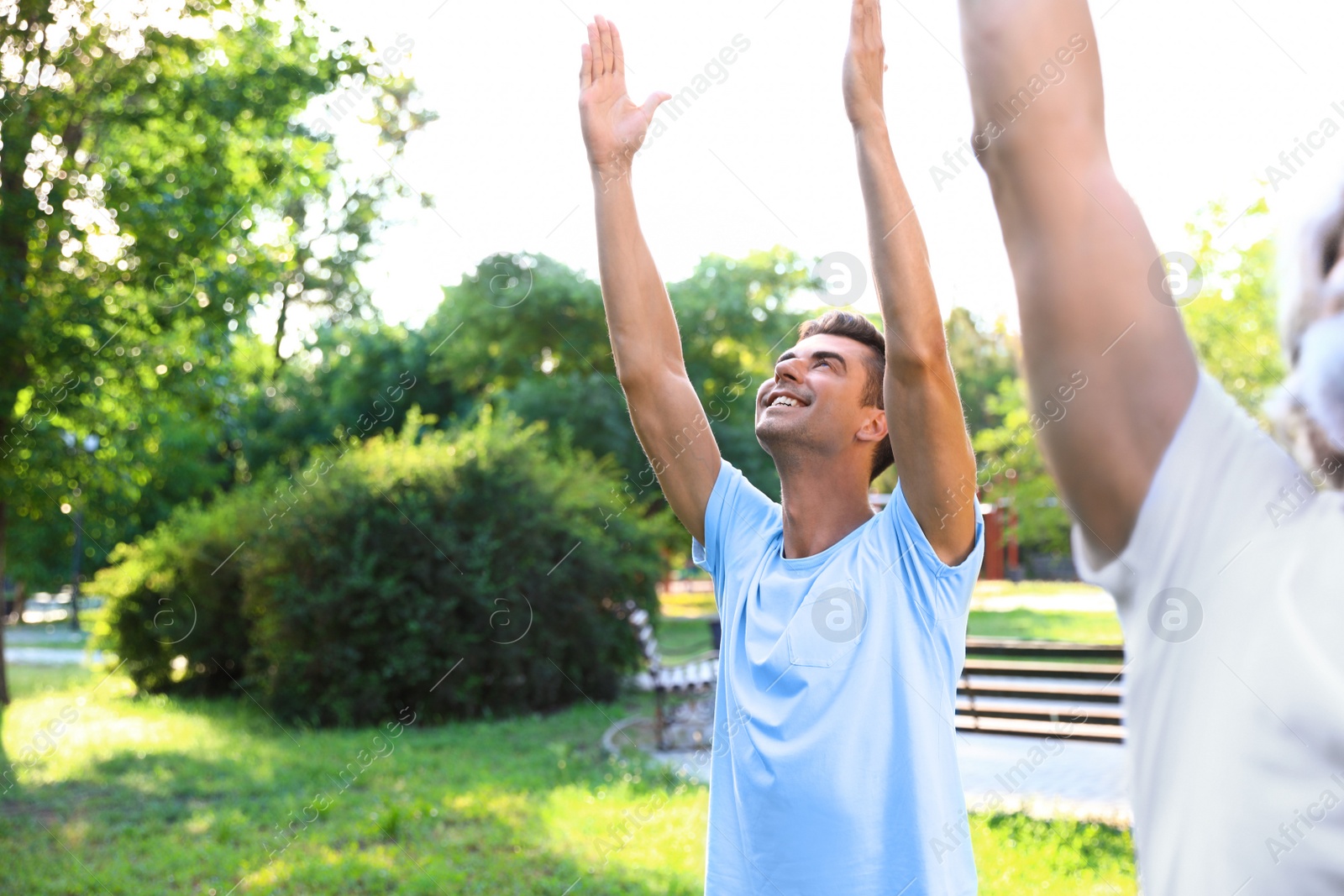 Photo of Men practicing morning yoga in sunny park. Space for text