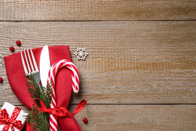 Photo of Cutlery set and festive decor on wooden table, flat lay with space for text. Christmas celebration