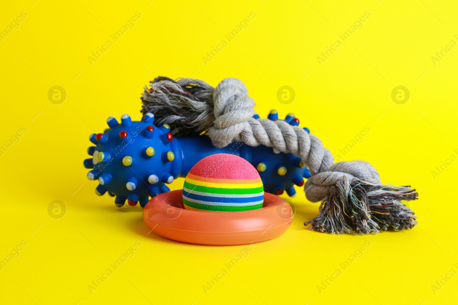 Photo of Different colorful pet toys on yellow background