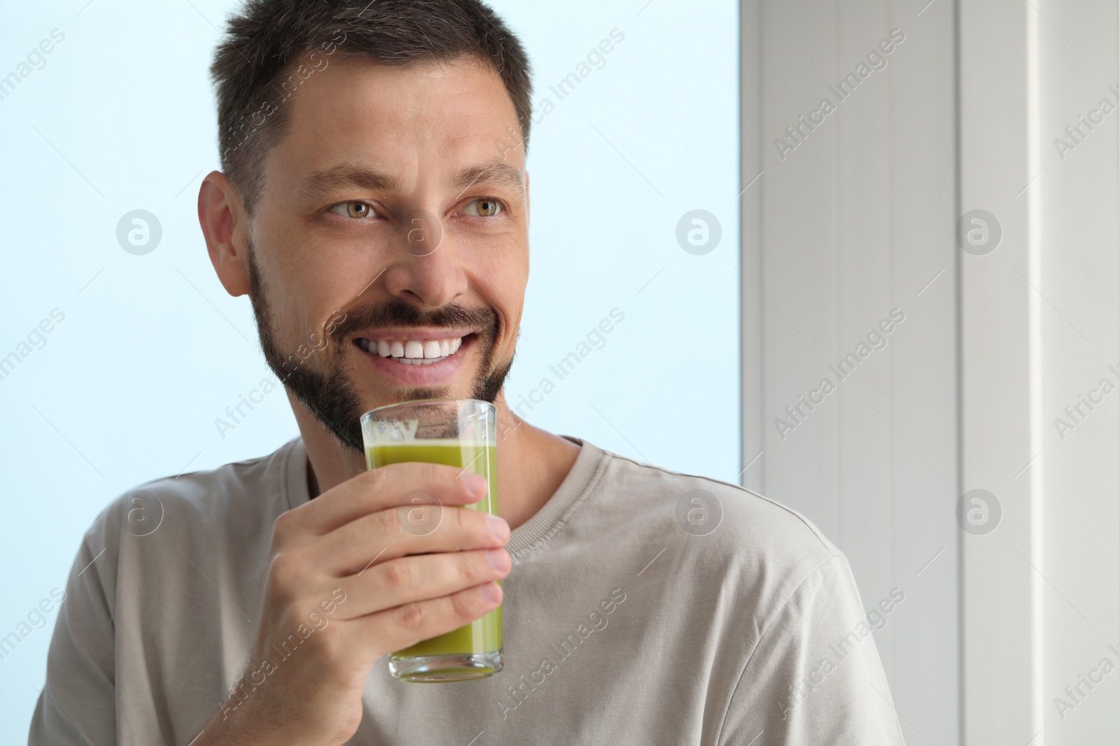 Photo of Man drinking delicious juice indoors, space for text