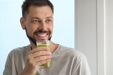 Photo of Man drinking delicious juice indoors, space for text