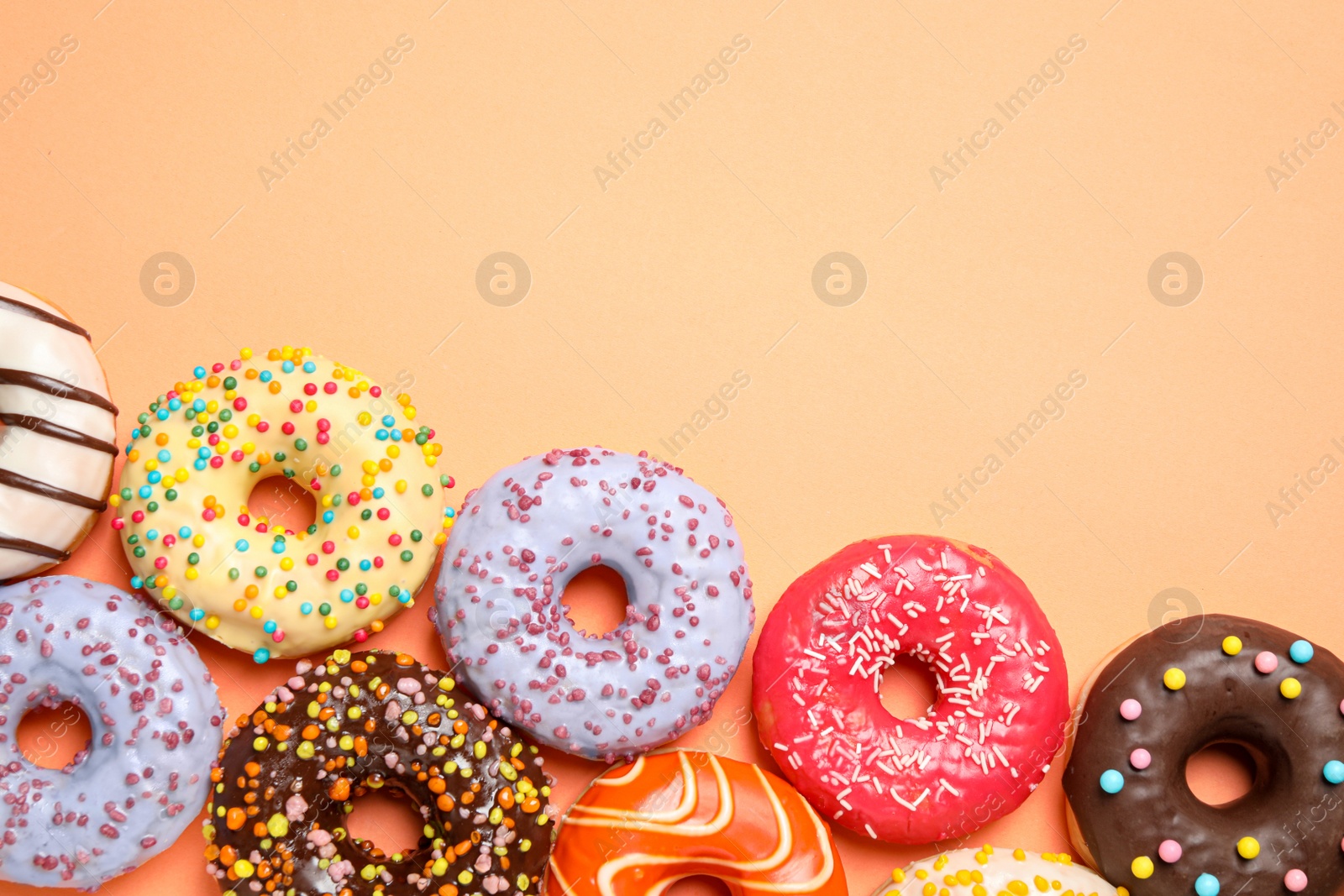 Photo of Delicious glazed donuts on orange background, flat lay. Space for text