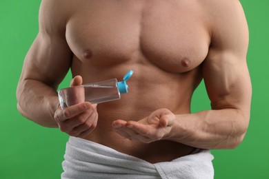 Photo of Man with body lotion on green background, closeup