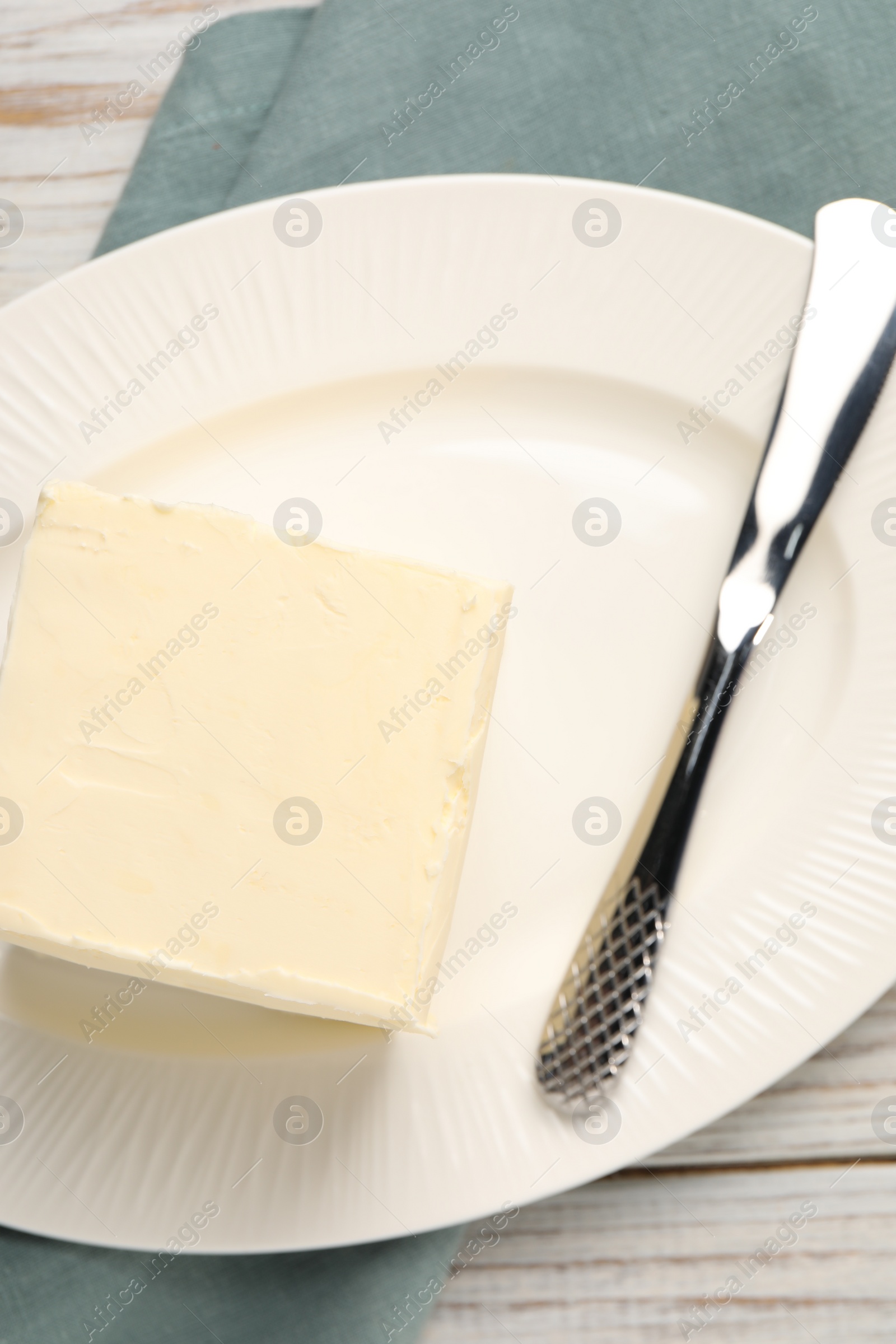 Photo of Block of tasty butter and knife on white wooden table