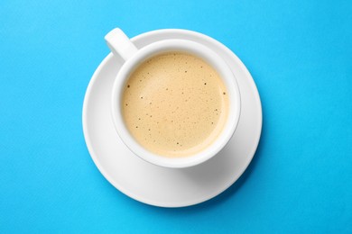 Aromatic coffee in cup on light blue background, top view