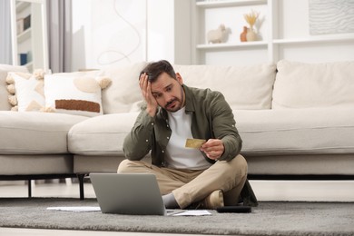 Photo of Confused man with laptop, debt notifications and credit card planning budget at home. Financial problem