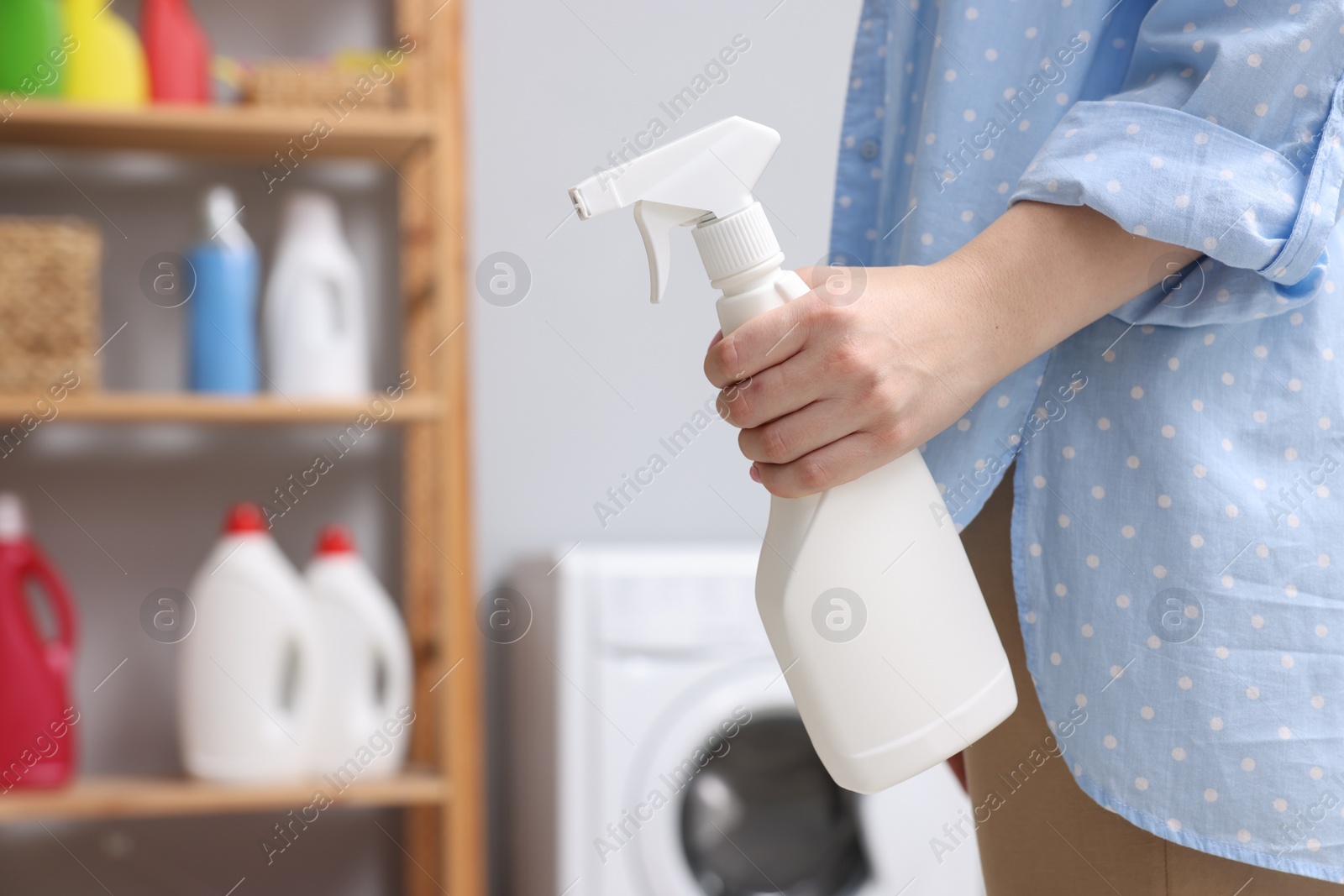 Photo of Woman with spray bottle in laundry room, closeup