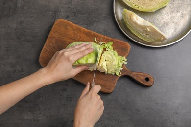 Woman cutting ripe cabbage at table, top view