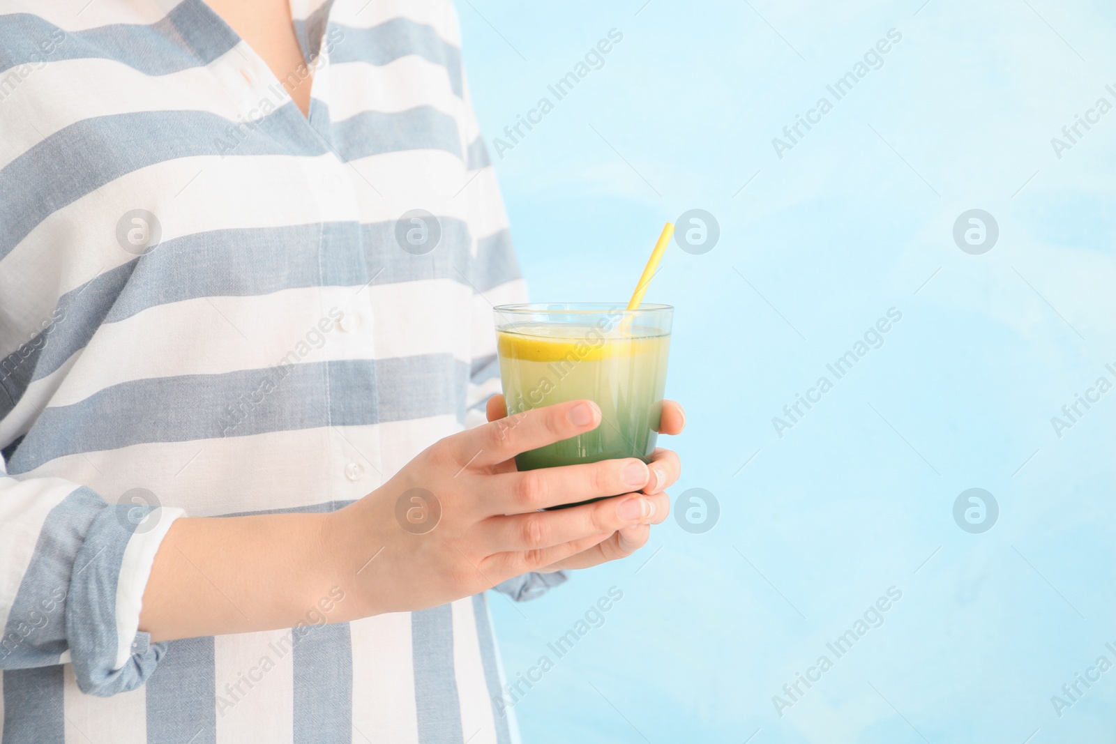 Photo of Young woman holding glass with lemon cocktail against light background