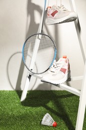 Photo of Composition with badminton equipment and sneakers against light background